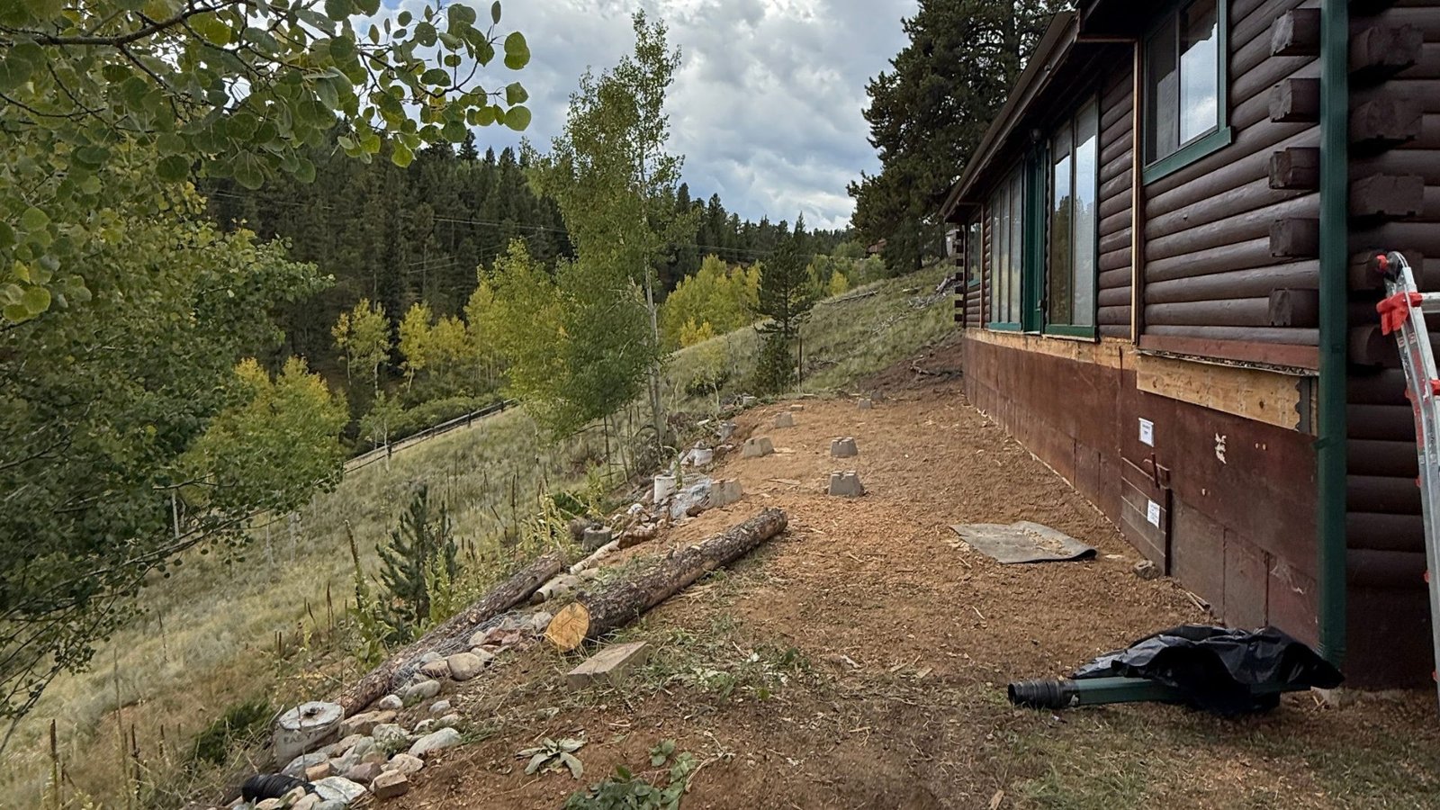 Hillside excavation and grading beside a log home foundation